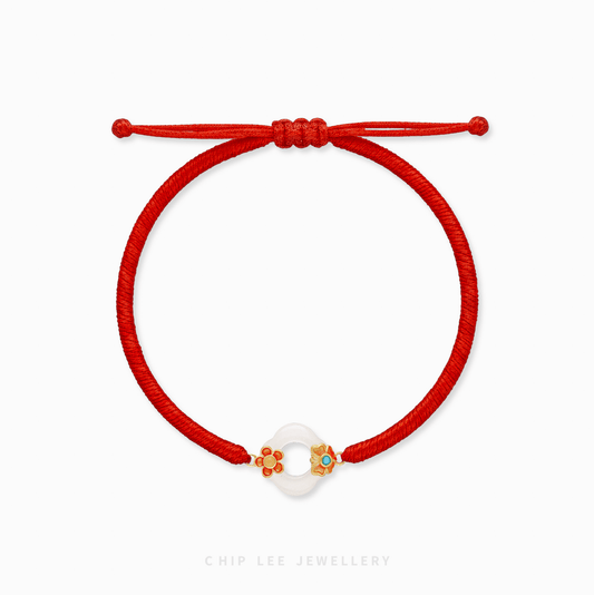 A close-up of a 999 Pure Gold Adjustable Baby Bracelet, showing the detailed gold floral piece and a smooth He Tian Yu (Jade) bead.