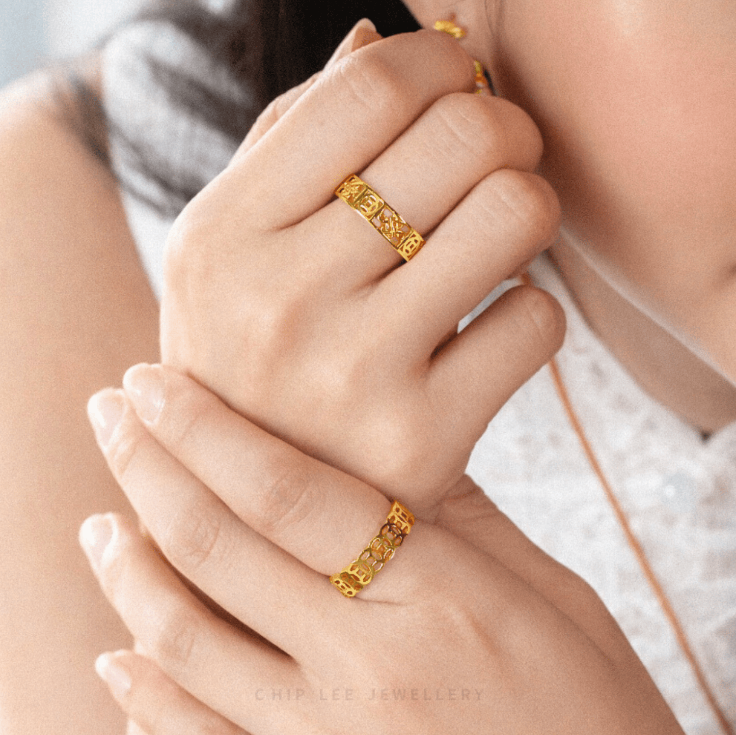 Close-up of hands wearing matching 916 gold rings with intricate Chinese-inspired motifs, symbolising harmony, blessings, and timeless craftsmanship.