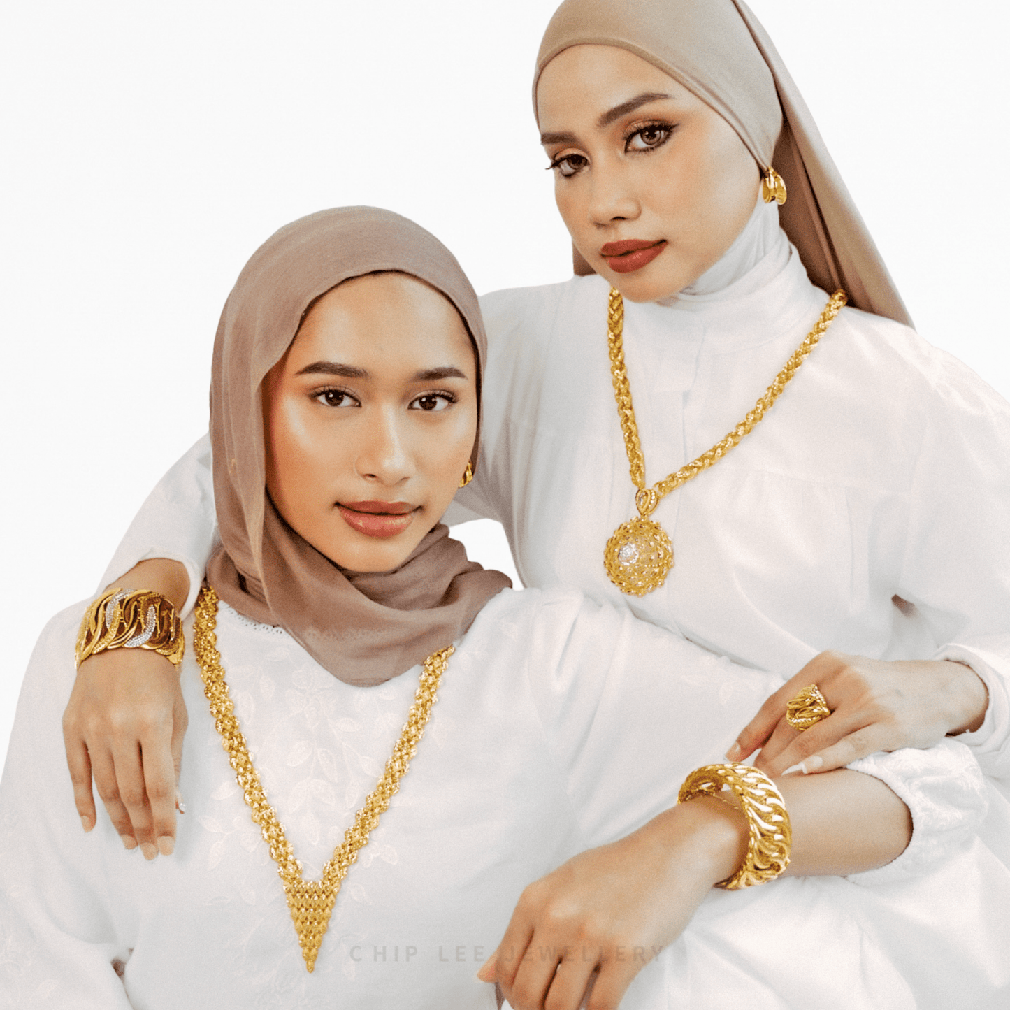 Two women wearing gold jewelry against a white background