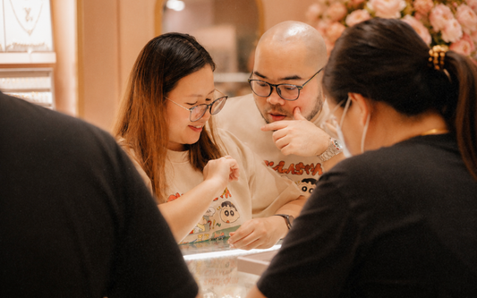 A couple selecting and purchasing gold jewellery at a jewellery store in Singapore, symbolising wedding and gift planning.