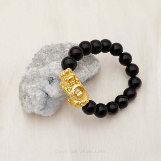 Close-up of 999 Pure Gold Black Agate Pixiu Bracelet with black agate beads and gold Pixiu charm on display.
