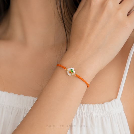 A close-up of a 999 Pure Gold Adjustable Baby Bracelet, showing the detailed gold floral piece and a smooth He Tian Yu (Jade) bead.