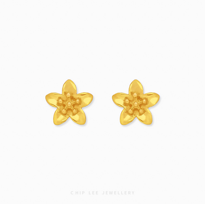 A pair of bright yellow 999 pure gold floral stud earrings with a detailed petal design and high-shine finish, presented on a white backdrop.