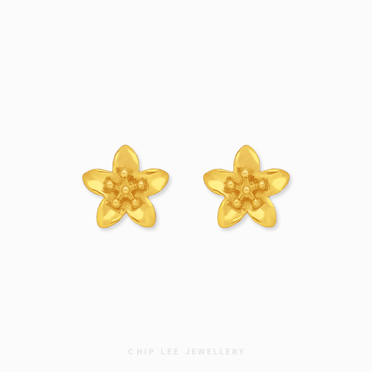 A pair of bright yellow 999 pure gold floral stud earrings with a detailed petal design and high-shine finish, presented on a white backdrop.