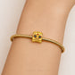 A gold-plated snake-braided bracelet with a lion head charm featuring red and black enamel details, shown worn on a person's wrist.