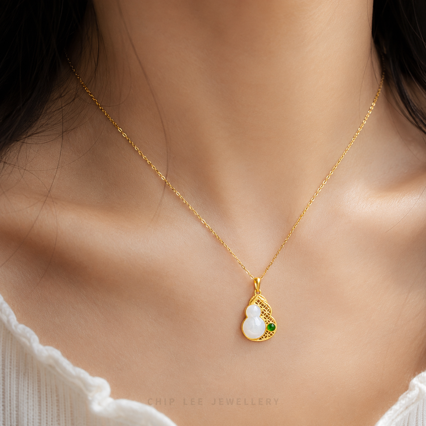 Gold pendant with a white jade and green gem on a white background