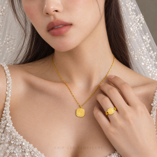A close-up lifestyle shot of a model wearing a gold pendant necklace and a matching gold ring, dressed in a white beaded bridal gown and veil. The brand name 'CHIP LEE JEWELLERY' is subtly visible at the bottom.
