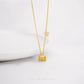 Gold necklace with a small lock charm pendant on a white background