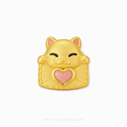 A gold cat-shaped charm with a pink glitter heart on its chest, featuring black line details for closed eyes and a smiling mouth, set against a plain white background.