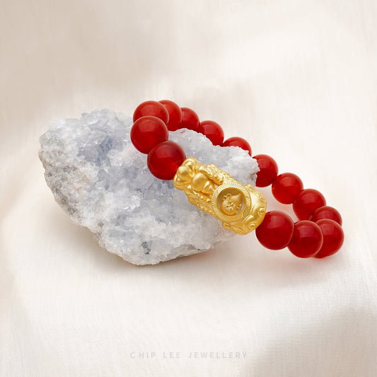 Close-up of 999 Pure Gold Red Agate Pixiu Bracelet with red agate beads and gold Pixiu charm on display.