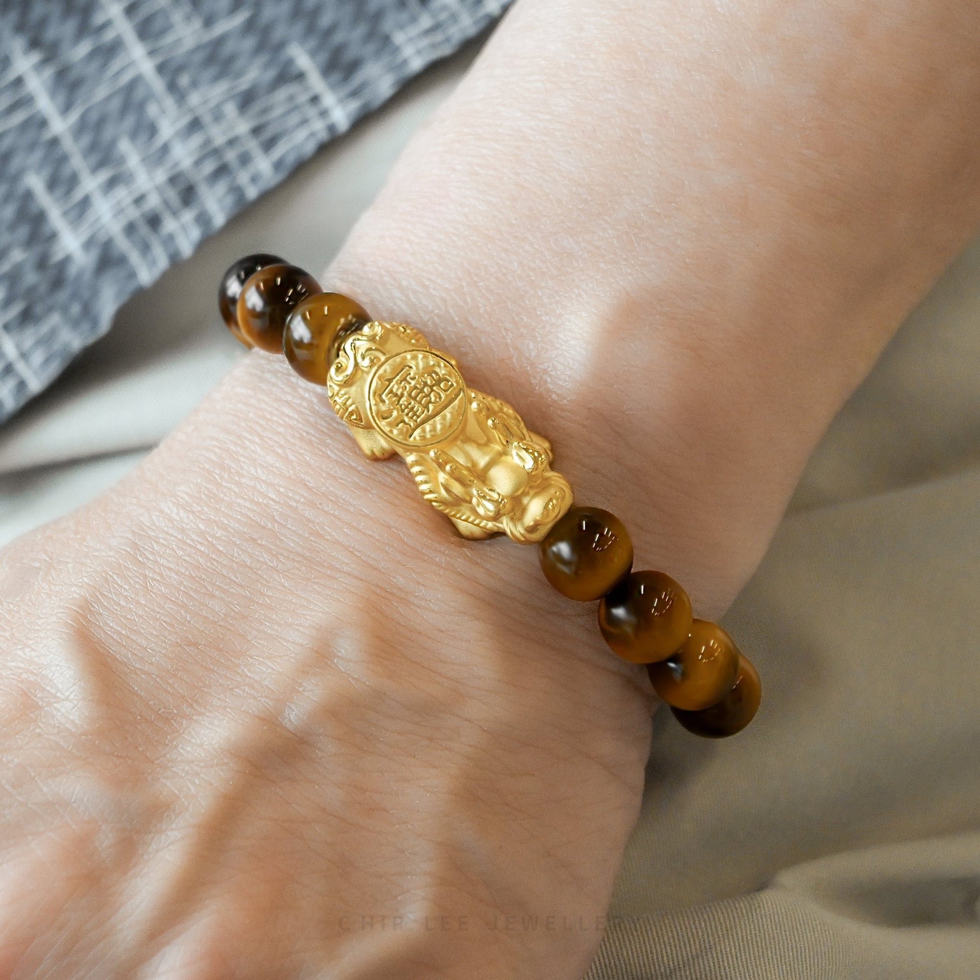 Close-up of 999 Pure Gold 招财纳福 Tiger Eye Pixiu Bracelet featuring a gold Pixiu charm and tiger eye beads on display.