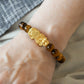 Close-up of 999 Pure Gold 招财纳福 Tiger Eye Pixiu Bracelet featuring a gold Pixiu charm and tiger eye beads on display.