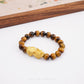 Close-up of 999 Pure Gold 招财纳福 Tiger Eye Pixiu Bracelet featuring a gold Pixiu charm and tiger eye beads on display.