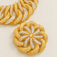 Gold and silver rhinestone-embellished chain link jewelry shown in a close-up studio shot on a light beige background.