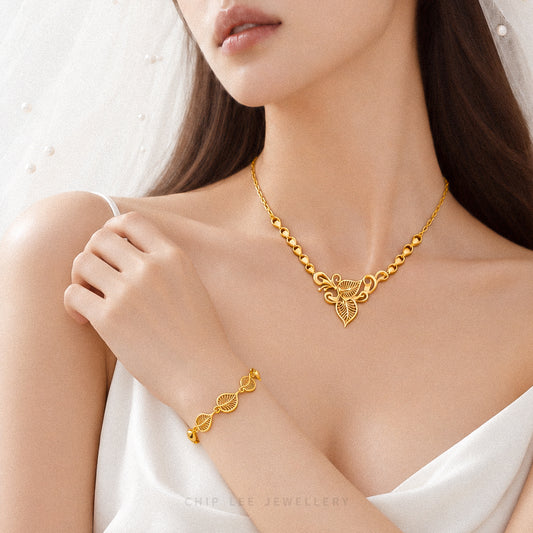 A close-up of a model wearing a gold necklace and matching bracelet from Chip Lee Jewellery, styled with a white bridal veil and white satin dress.