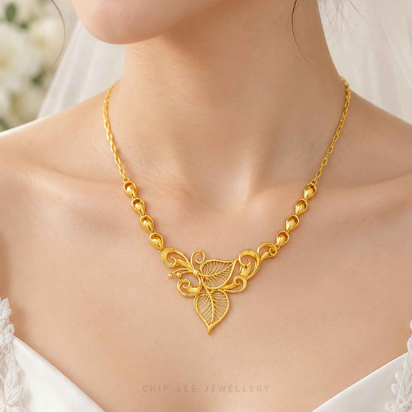 A close-up of a woman wearing a gold necklace with a leaf and scrollwork pendant, styled with a white bridal veil and white lace top. The brand name 'CHIP LEE JEWELLERY' is visible at the bottom.