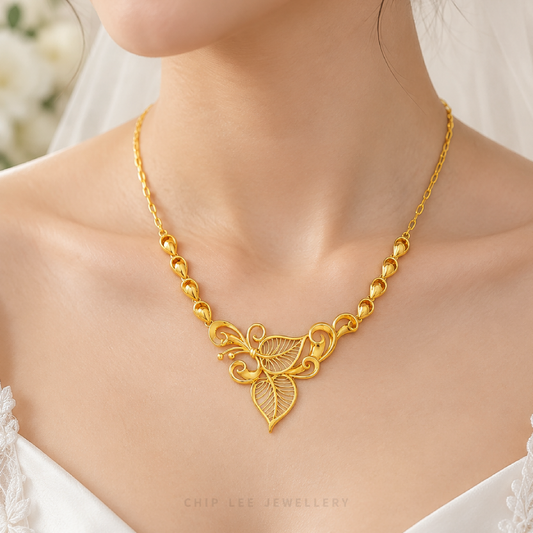 A close-up of a woman wearing a gold necklace with a leaf and scrollwork pendant, styled with a white bridal veil and white lace top. The brand name 'CHIP LEE JEWELLERY' is visible at the bottom.