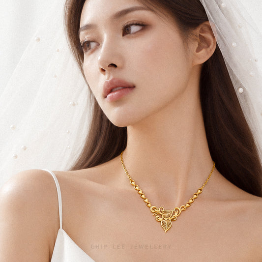 A close-up of a woman wearing a delicate gold necklace with a heart-shaped pendant, styled with a white bridal veil and white spaghetti-strap top. The brand name 'CHIP LEE JEWELLERY' is subtly printed at the bottom.