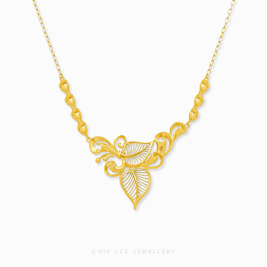 A gold necklace with a floral motif pendant at the center, displayed against a white background.
