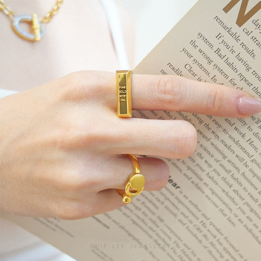 Gold rings on a finger with a blurred book background