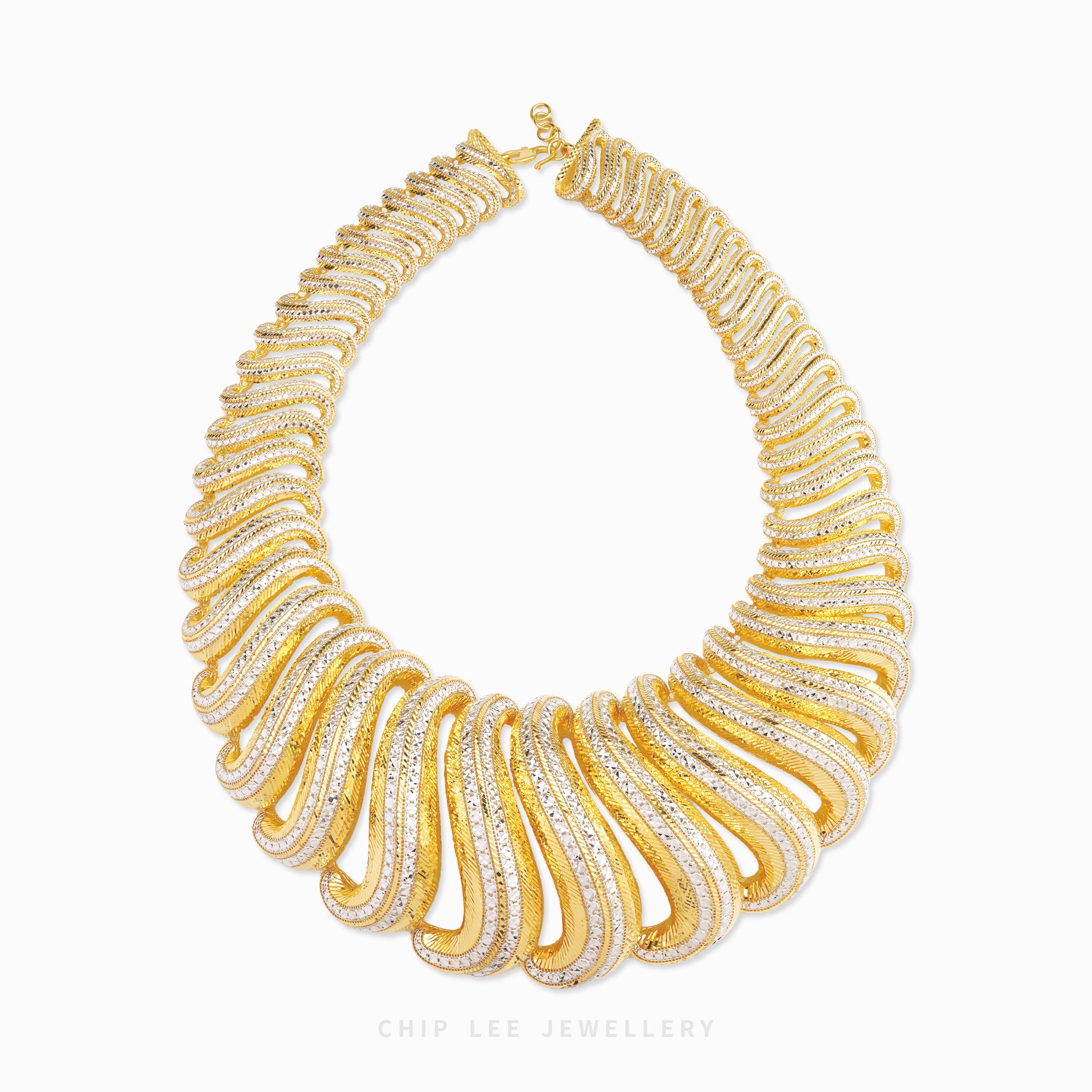 A chunky gold statement necklace by Chip Lee Jewellery, featuring a wide, layered design of sculptural, ridged bands set with clear pavé stones, photographed on a clean white background.
