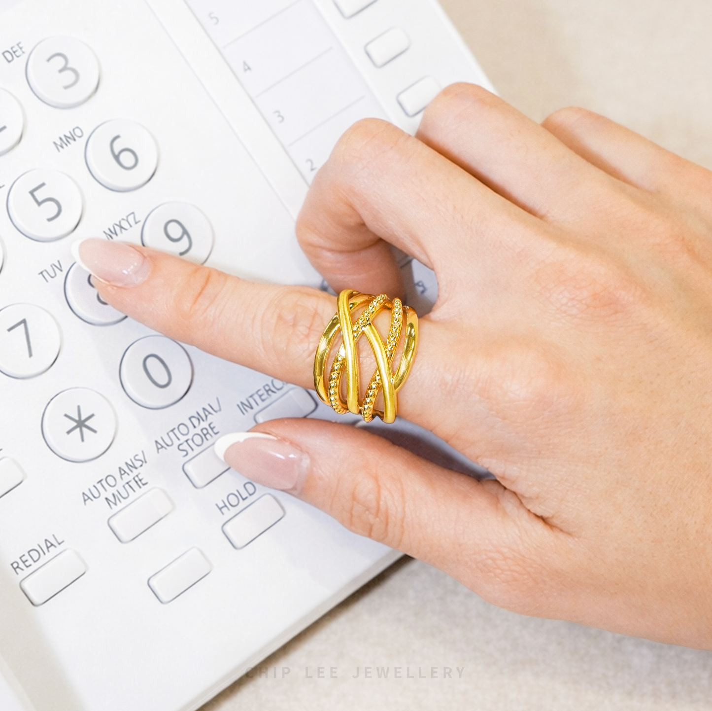 Hand wearing a gold ring on a white telephone 