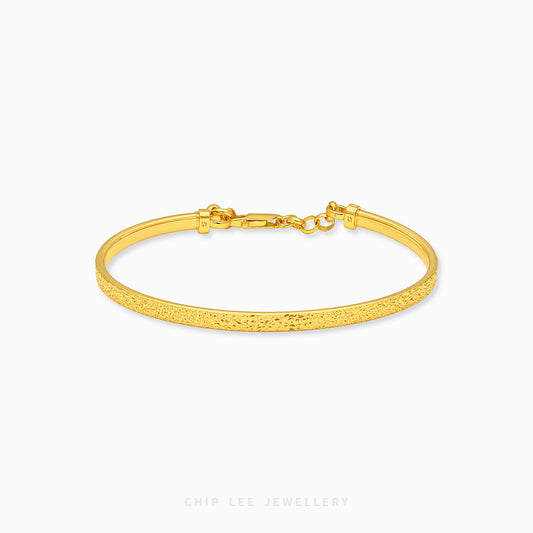 A textured yellow gold hinged bangle bracelet with a lobster clasp, shown on a clean white background with the brand name 'CHIP LEE JEWELLERY' at the bottom.