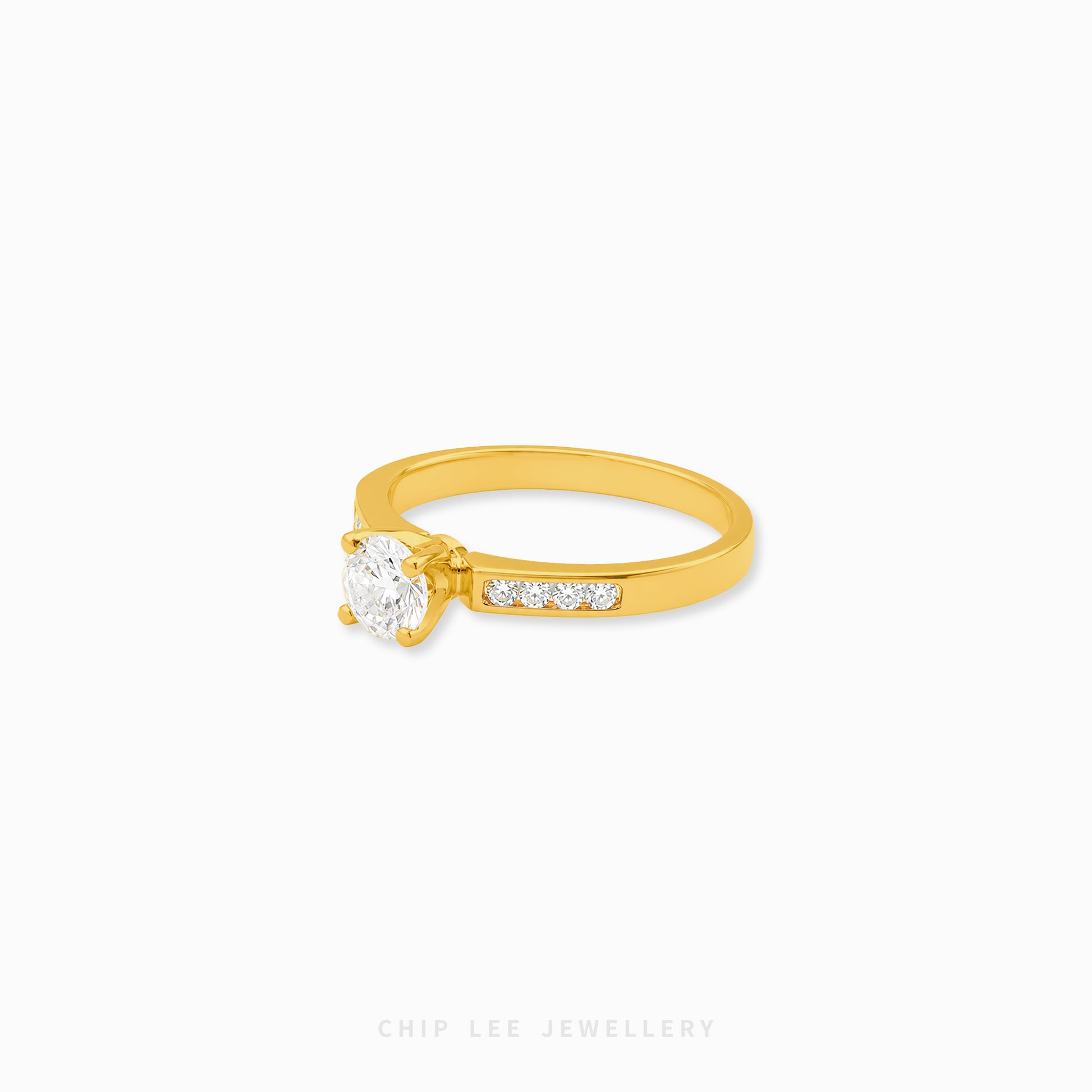 A yellow gold solitaire ring with a round-cut clear center stone and a row of small pavé-set clear stones on the band, shown on a plain white background. The brand name 'CHIP LEE JEWELLERY' is faintly visible at the bottom.