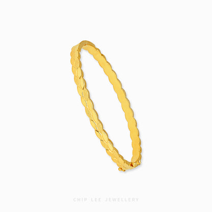 A gold bangle bracelet with a textured, ridged pattern, shown on a clean white background with a brand watermark at the bottom.