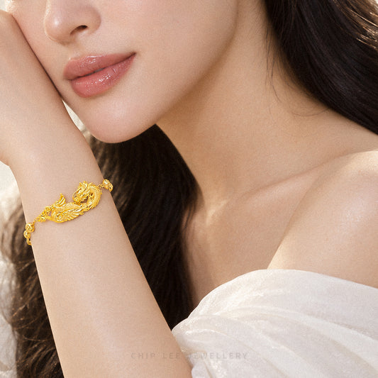 A close-up lifestyle shot of a woman wearing a detailed gold dragon bracelet on her wrist, with her face and shoulder visible against a soft neutral background.