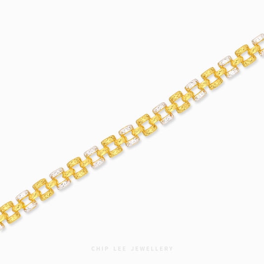 A gold link bracelet with alternating textured yellow-gold links and clear crystal links, displayed on a clean white background with a brand watermark at the bottom.