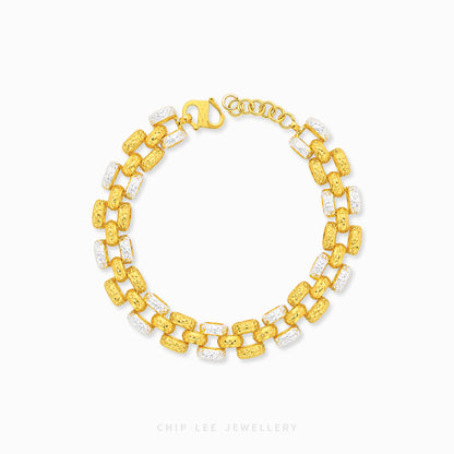 A gold link bracelet with alternating textured yellow-gold links and clear crystal links, displayed on a clean white background with a brand watermark at the bottom.