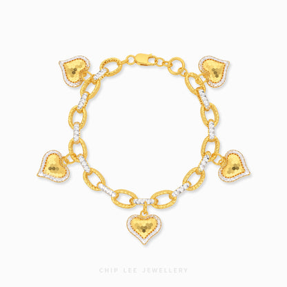 Gold bracelet with heart-shaped charms on a white background