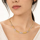 Gold necklace with embedded stones worn by a model on a white background
