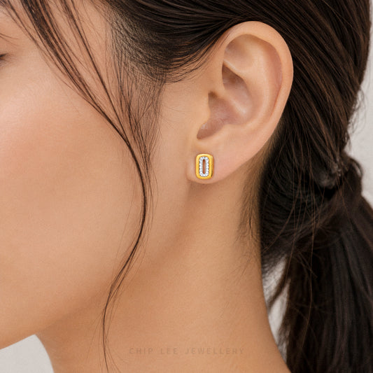 Close-up of an ear wearing a gold earring with a blurred background