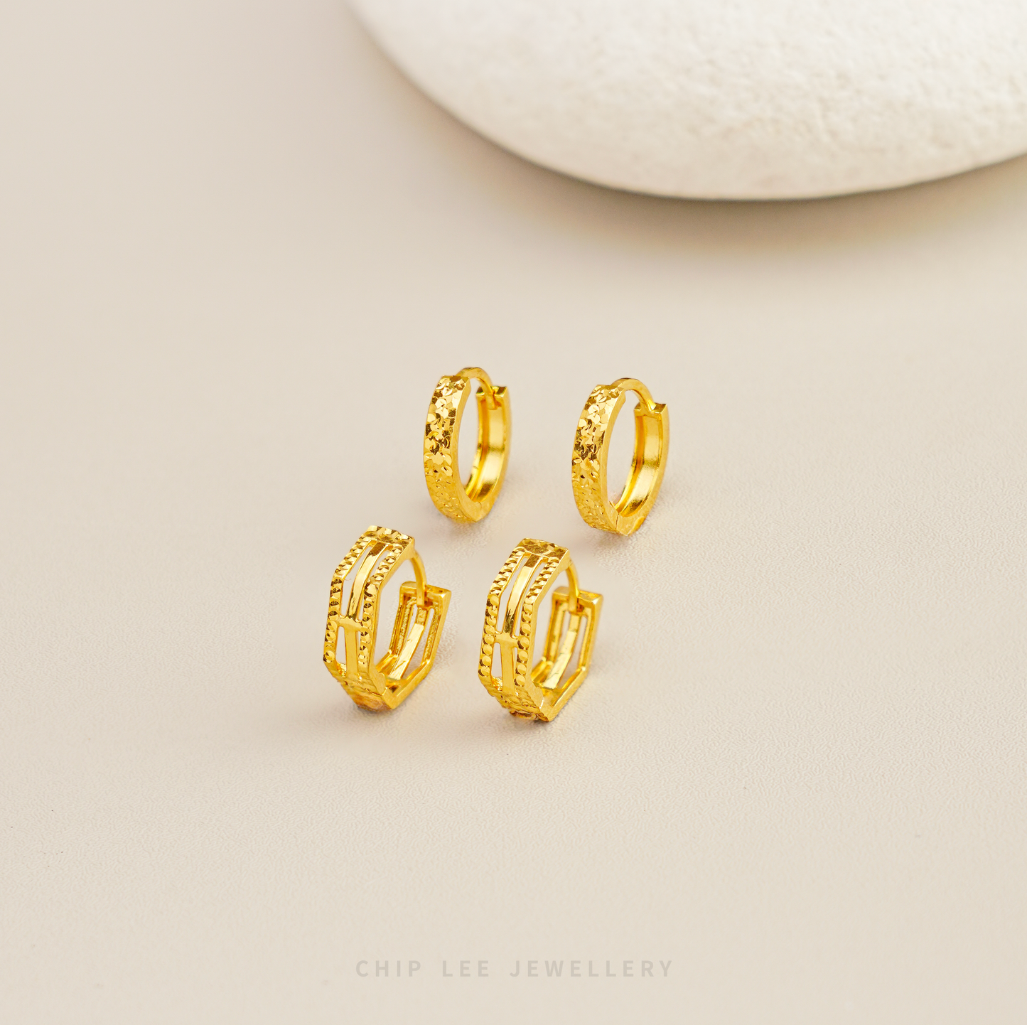 Gold hoop earrings on a beige background with 'Chip Lee Jewellery' branding.