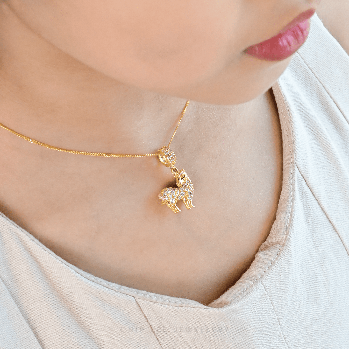 Gold necklace with a unicorn pendant worn by a person