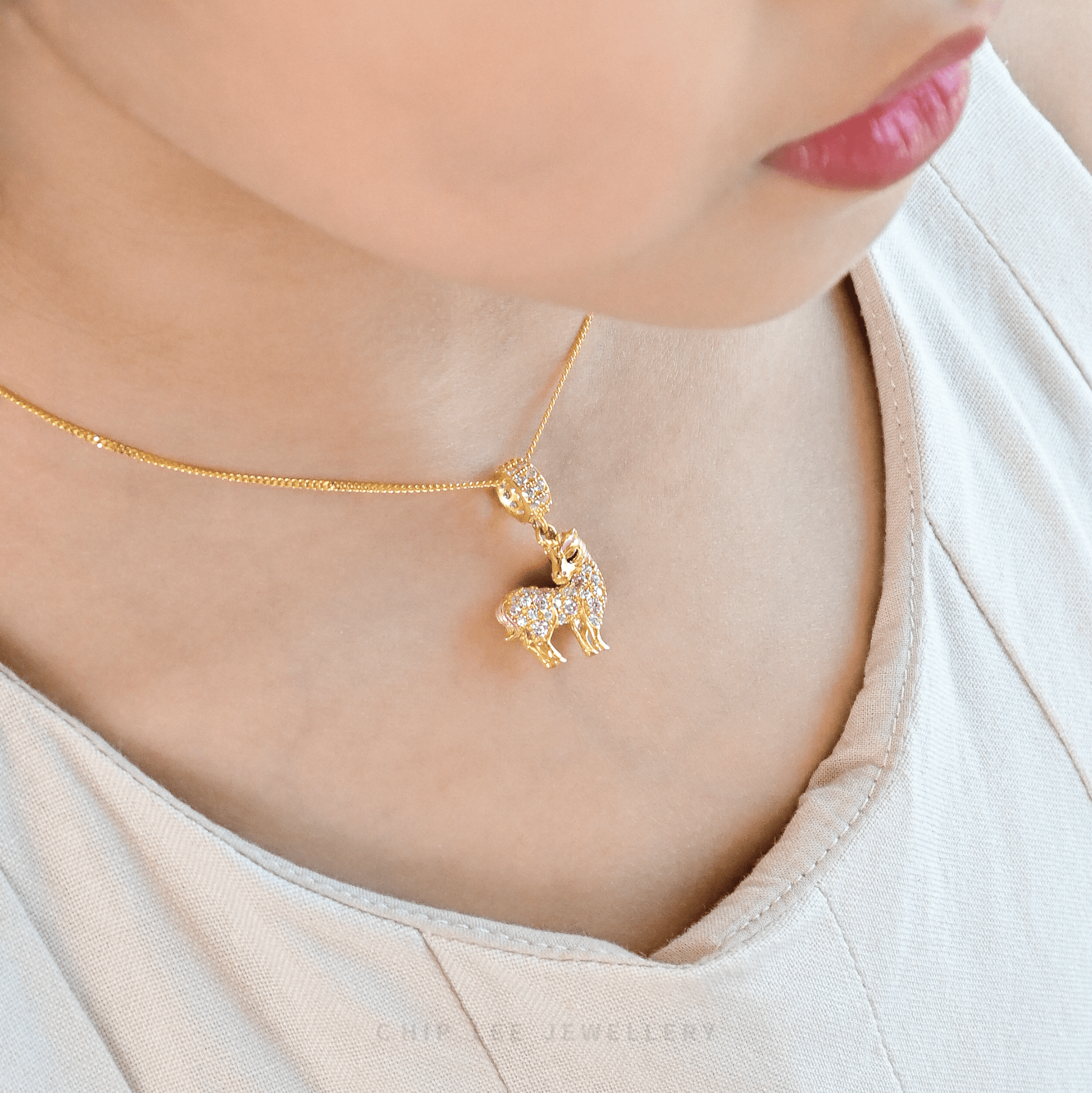 Gold necklace with a unicorn pendant worn by a person