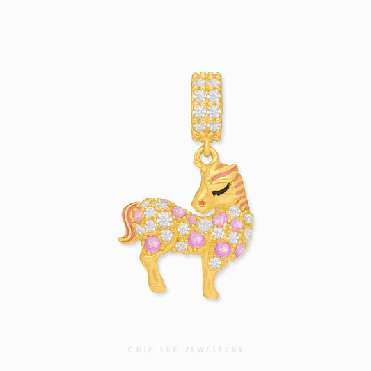 A gold charm in the shape of a unicorn with pink and white enamel details.
