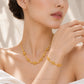 A close-up lifestyle shot of a model wearing a delicate gold necklace and matching bracelet from Chip Lee Jewellery. The jewelry features small, repeating floral/starburst motifs connected by tiny gold beads.
