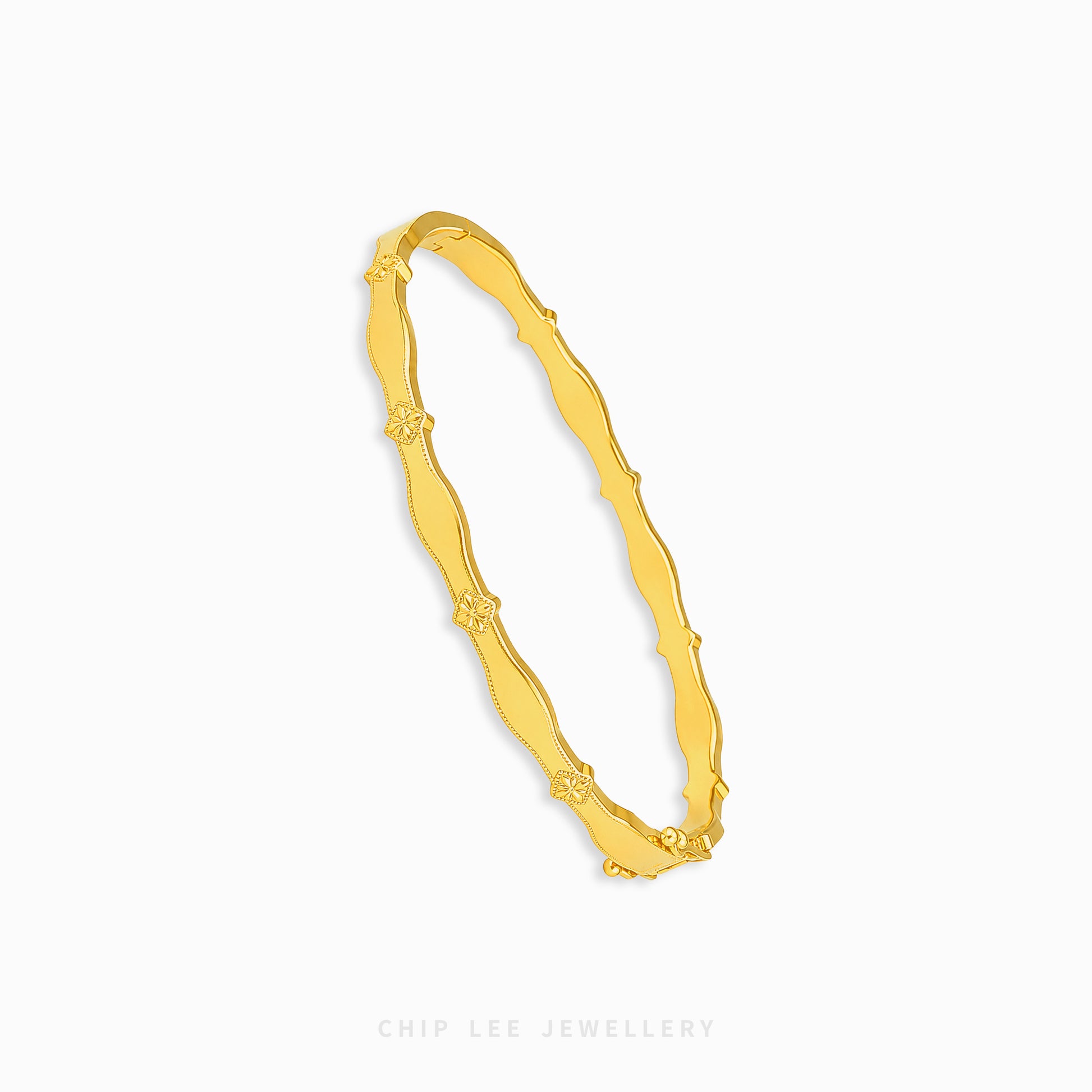 A gold bangle bracelet with a wavy, textured design and small floral details spaced along the band, shown on a plain white background with the brand name 'CHIP LEE JEWELLERY' printed at the bottom.