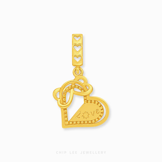 A gold heart-shaped charm with an interlocking heart design and a top bar featuring three heart cutouts, shown on a light gray background with a Chip Lee Jewellery watermark.