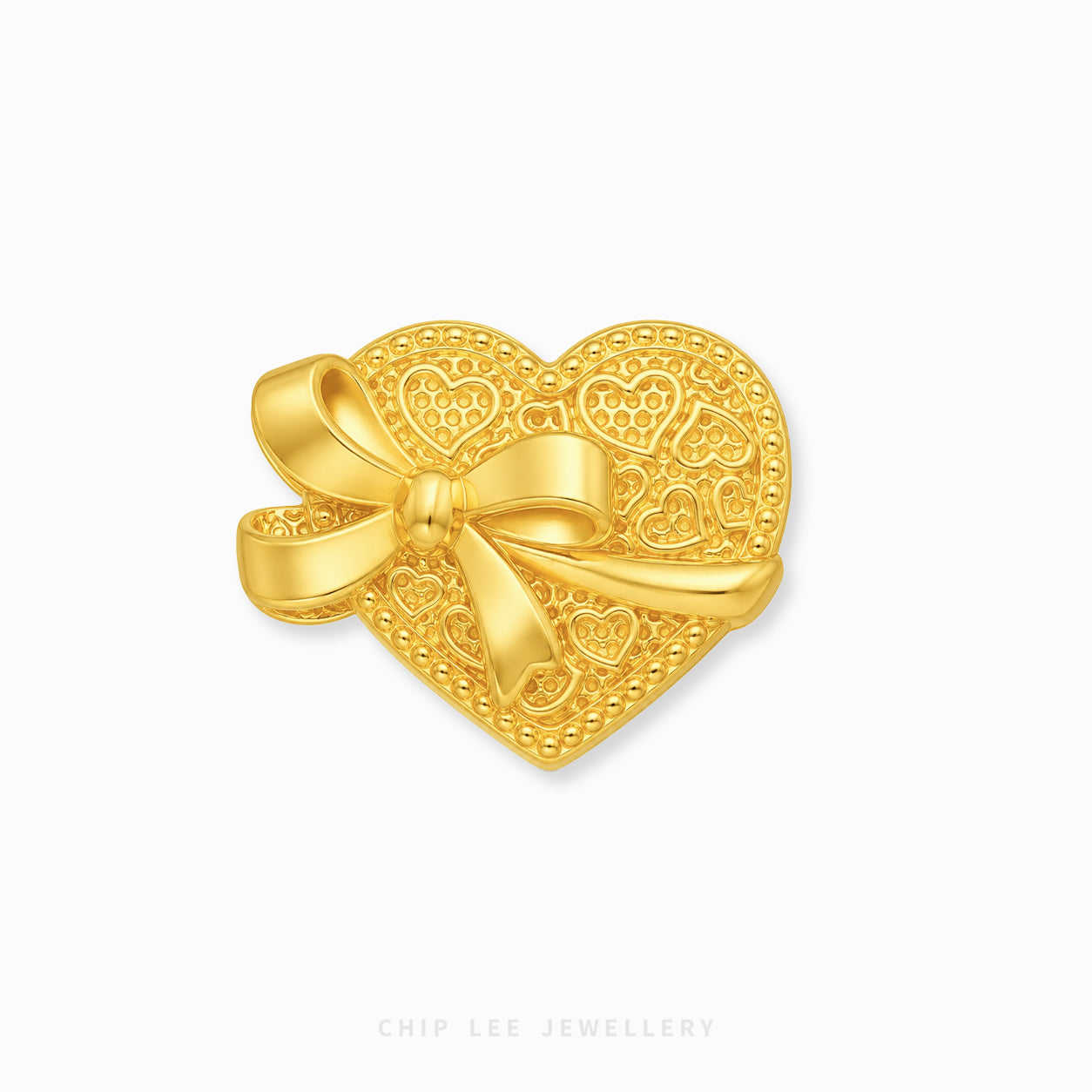 A gold heart-shapedcharm with an intricate filigree pattern and a large bow on the left side, shown on a clean white background with a faint 'CHIP LEE JEWELLERY' watermark at the bottom.