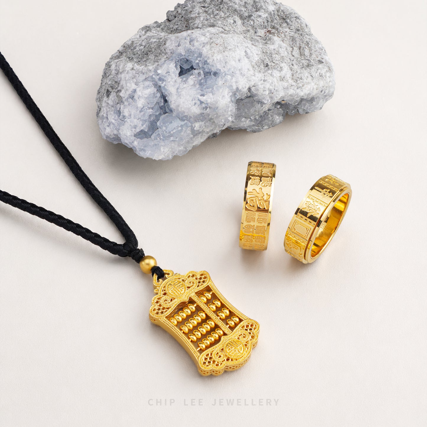 Gold necklace and rings on a white background with a rock.