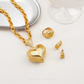 Gold heart-shaped necklace, ring, and earrings on a white surface with 'Chip Lee Jewellery' branding.