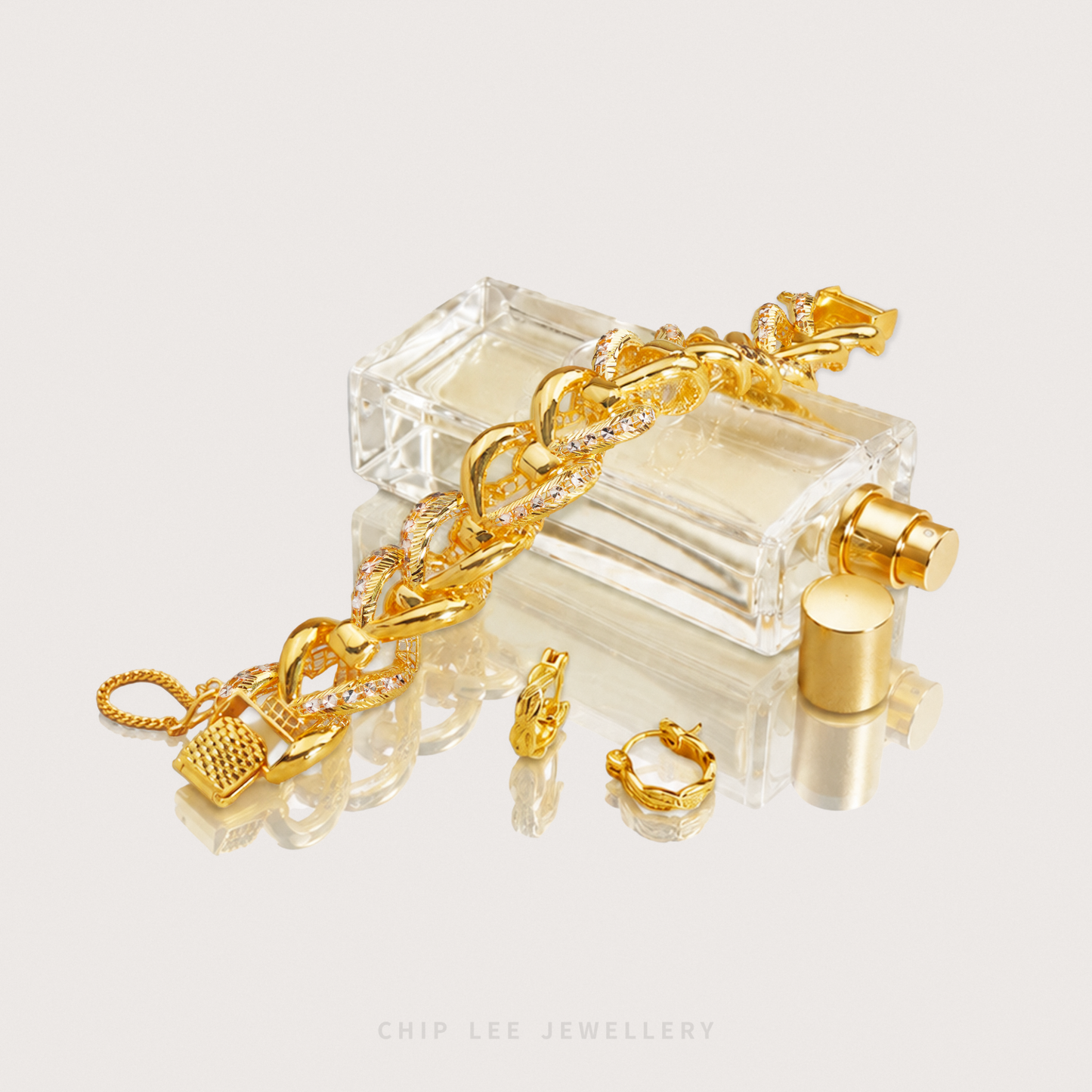 Gold bracelet and earrings on a clear glass stand with 'Chip Lee Jewellery' branding.