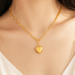 A close-up of a model's neck and chest wearing a delicate gold chain necklace with a small polished heart-shaped pendant. The image features a warm, soft glow and has 'CHIP LEE JEWELLERY' text printed at the bottom.