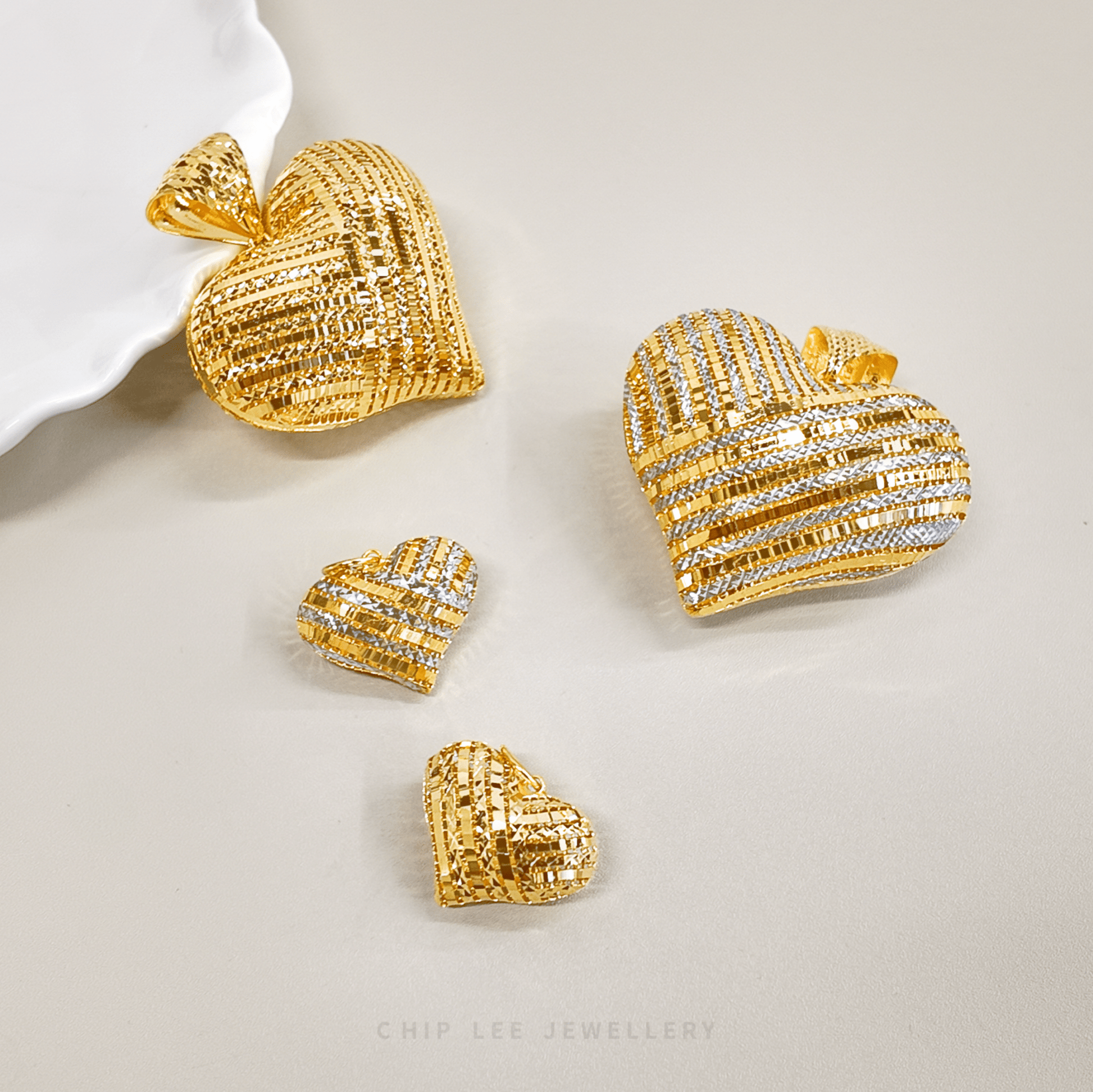 Gold heart-shaped jewelry pieces on a light background with 'Chip Lee Jewellery' branding.