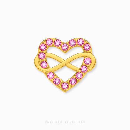 A gold heart-shaped brooch featuring an infinity symbol in the center, adorned with small round pink gemstones along the outer edges, shown on a light gray background.