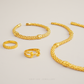 Gold jewelry including a necklace, bracelet, and rings on a light gray background.